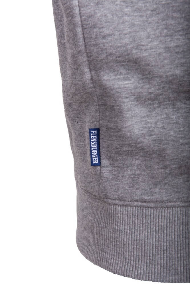 Detailansicht eines grauen Pullovers. Am Ärmel ist das Etikett "Flensburger" sichtbar.