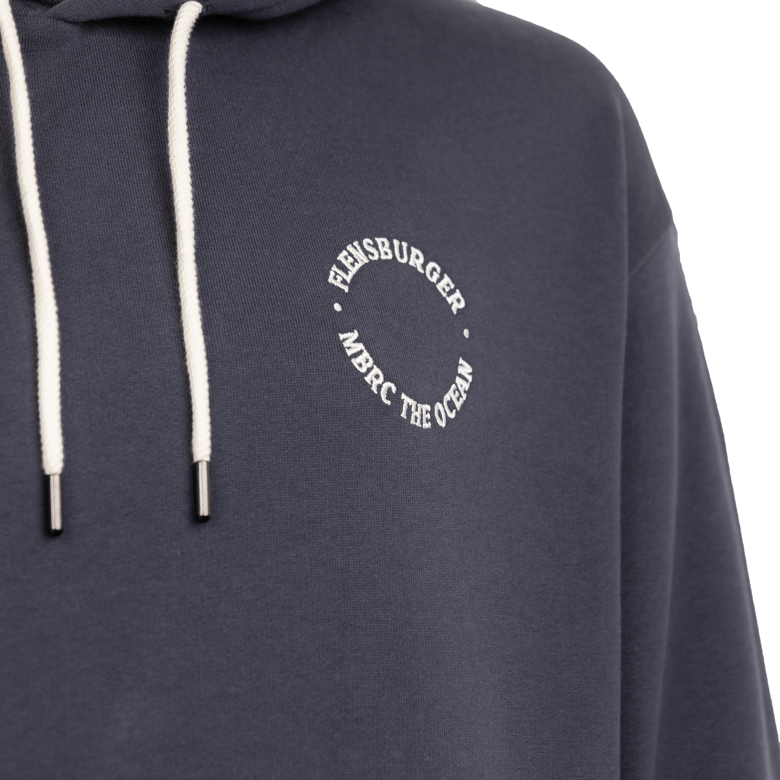 Detailansicht: Anthrazitfarbener Hoodie mit weißen Kordeln. Auf der Brust ist ein runder, weißer Schriftzug „FLENSBURGER • MBRC THE OCEAN“ zu sehen.